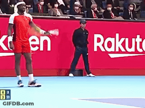 A Man Is Holding A Tennis Racquet On A Tennis Court In Front Of A Rakuten Sign . GIF