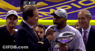 A Man Is Holding A Trophy And Talking Into A Microphone GIF