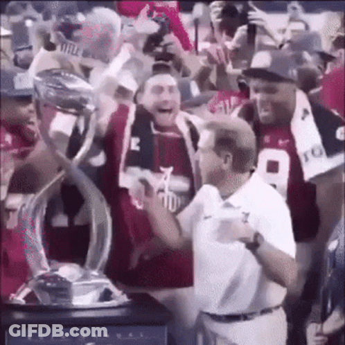 A Man Is Holding A Trophy In A Crowd Of People . GIF