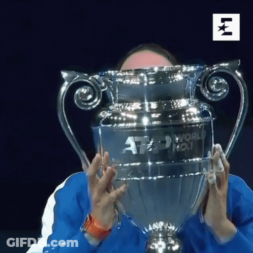 A Man Is Holding A Trophy In Front Of His Face That Says Atp World No. 1 GIF
