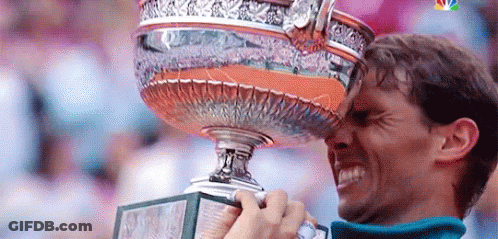 A Man Is Holding A Trophy In His Hand And Kissing It On His Forehead . GIF