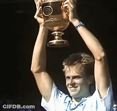 A Man Is Holding A Trophy In His Hands GIF