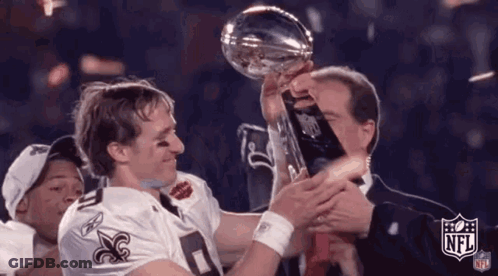 A Man Is Holding A Trophy In His Hands While A Man In A Suit Holds A Trophy . GIF