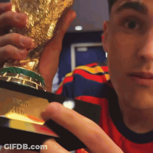 A Man Is Holding A Trophy That Says ' World Cup ' On It GIF