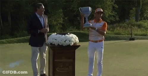 A Man Is Holding A Trophy While Standing Next To A Podium With Flowers GIF
