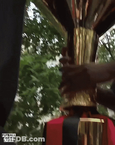 A Man Is Holding A Trophy With The Words Futball Karim Written On The Bottom GIF