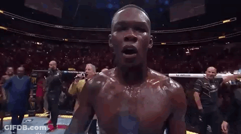 A Man Is Holding A Ufc Heavyweight Championship Belt In Front Of A Crowd Of People . GIF