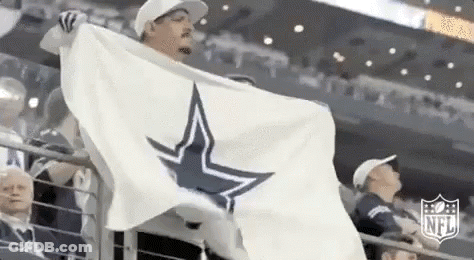 A Man Is Holding A White Flag With A Cowboys Star On It In A Stadium . GIF
