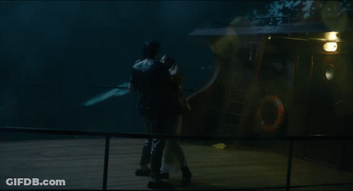 A Man Is Holding A Woman In A White Dress In The Rain GIF