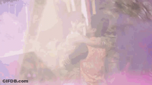 A Man Is Holding A Woman In His Arms And They Are Dancing Together . GIF