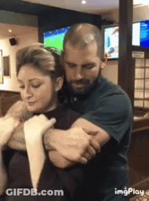 A Man Is Holding A Woman In His Arms In A Restaurant . GIF