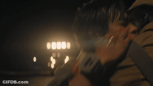 A Man Is Holding A Woman In His Arms In The Dark . GIF