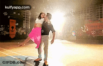A Man Is Holding A Woman In His Arms On A Basketball Court Surrounded By Bubbles . GIF