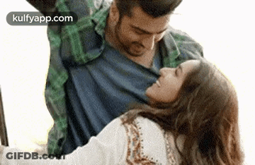 A Man Is Holding A Woman In His Arms While They Are Dancing Together . GIF