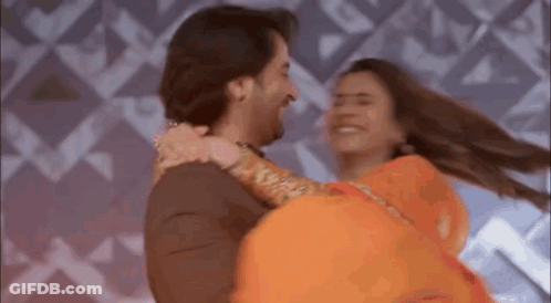 A Man Is Holding A Woman In His Arms While They Are Dancing Together . GIF