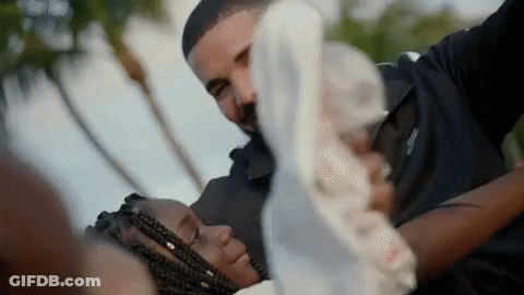 A Man Is Holding A Woman In His Arms While They Are Laying Down . GIF