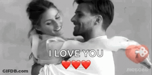 A Man Is Holding A Woman In His Arms With The Words `` I Love You '' Written On It . GIF