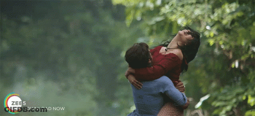 A Man Is Holding A Woman In His Arms With The Words Zee5 Download Now On The Bottom Right GIF