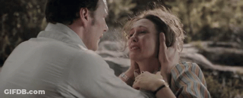 A Man Is Holding A Woman 'S Face While She Is Crying And Covering Her Ears . GIF