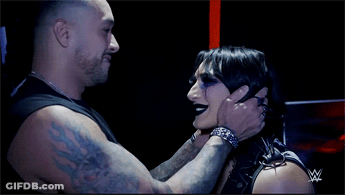 A Man Is Holding A Woman 'S Face With A W Logo In The Background GIF
