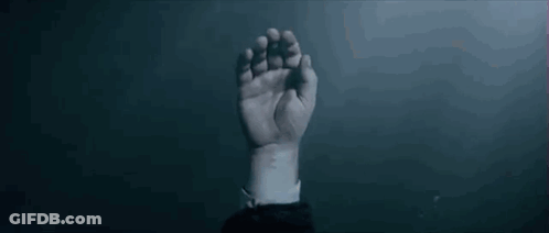 A Man Is Holding A Woman 'S Hand In A Dark Room . GIF