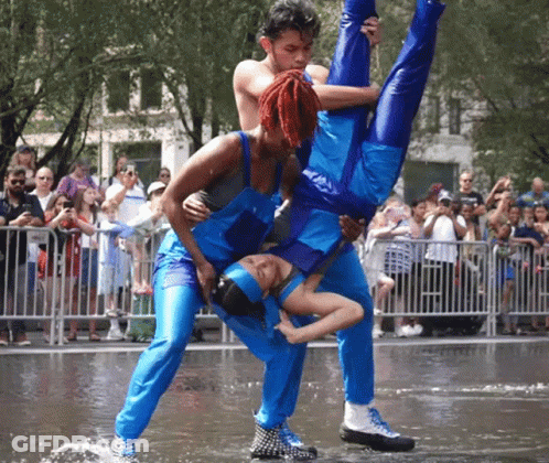 A Man Is Holding A Woman Upside Down In The Air While A Crowd Watches GIF