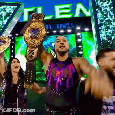 A Man Is Holding A Wrestling Championship Belt In Front Of A Sign That Says " T-Len " GIF