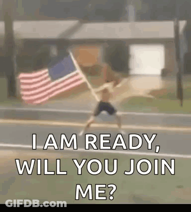 A Man Is Holding An American Flag On The Side Of A Road . GIF