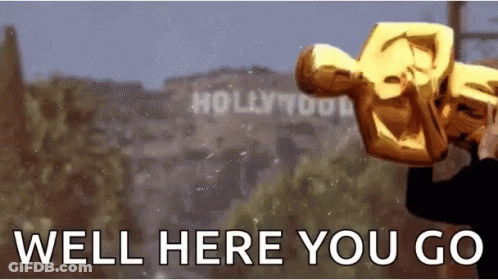 A Man Is Holding An Oscar Statue In Front Of A Sign That Says Hollywood GIF