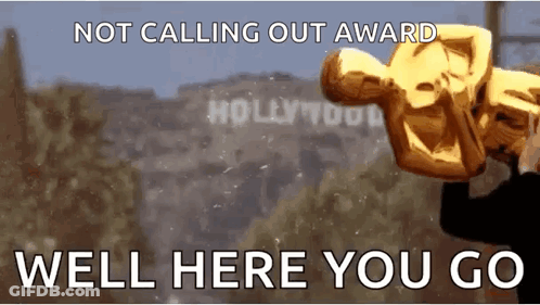A Man Is Holding An Oscar Statue In Front Of Hollywood Sign GIF