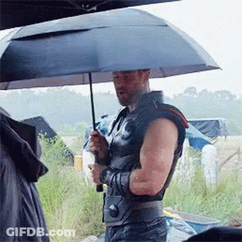 A Man Is Holding An Umbrella In The Rain GIF