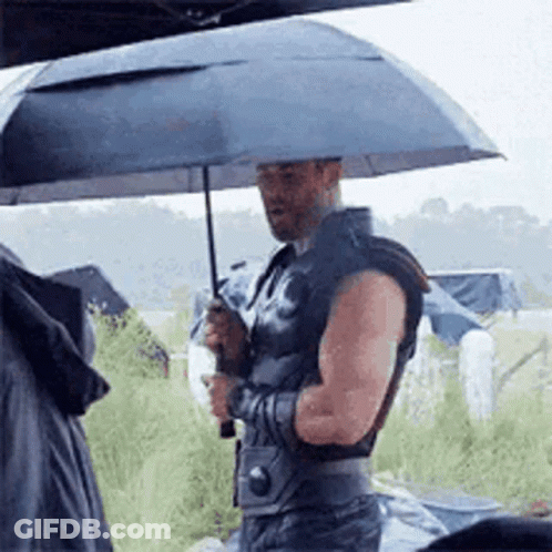 A Man Is Holding An Umbrella In The Rain While Wearing Armor . GIF