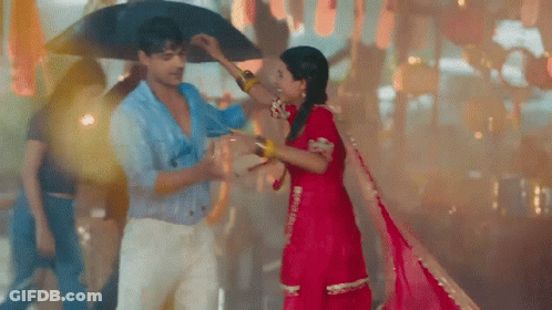 A Man Is Holding An Umbrella Over A Woman 'S Head . GIF