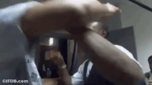A Man Is Holding Another Man 'S Arm In A Room While They Are Fighting . GIF