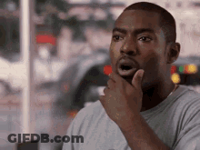 A Man Is Holding His Hand To His Chin And Making A Funny Face . GIF