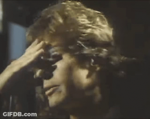 A Man Is Holding His Hand To His Forehead . GIF