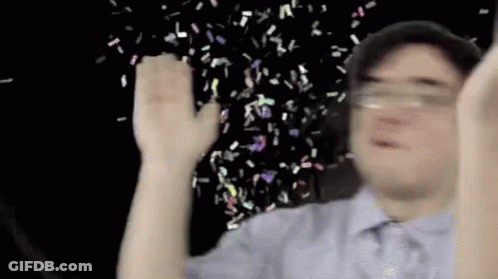 A Man Is Holding His Hands Up In The Air While Confetti Is Falling From The Sky . GIF