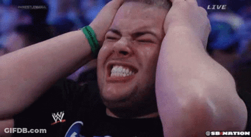 A Man Is Holding His Head In Pain While Watching A Wrestling Match On Sb Nation . GIF