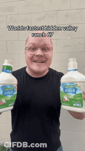 A Man Is Holding Two Bottles Of Ranch Dressing GIF