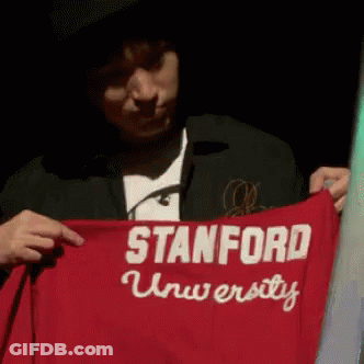 A Man Is Holding Up A Red Stanford University Shirt GIF