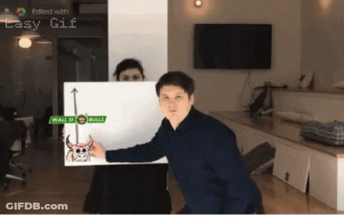 A Man Is Holding Up A Sign That Says Wall St Bulls GIF