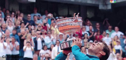 A Man Is Holding Up A Trophy In Front Of A Crowd Of People . GIF