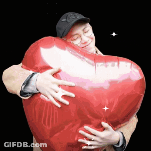 A Man Is Hugging A Heart Shaped Balloon With The Letter P On His Hat GIF