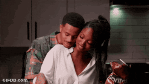 A Man Is Hugging A Woman In A Kitchen With Doritos Chips In The Background GIF