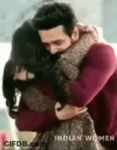 A Man Is Hugging A Woman In A Living Room . GIF