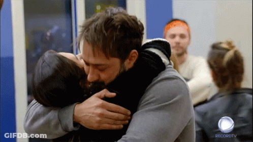 A Man Is Hugging A Woman In Front Of A Recordtv Logo GIF