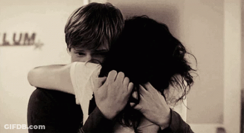 A Man Is Hugging A Woman In Front Of A Sign That Says Lume GIF