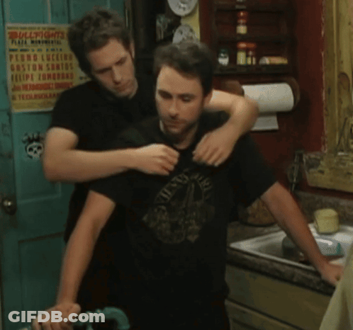 A Man Is Hugging Another Man In Front Of A Sign That Says Bullfights GIF