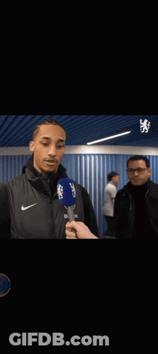 A Man Is Hugging Another Man While Holding A Microphone That Says Cbs On It GIF