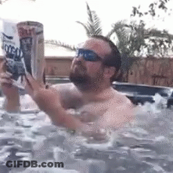 A Man Is In A Hot Tub Reading A Magazine GIF
